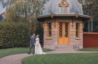 A bride and groom smiling in front of a gazebo on their wedding day