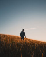 Silhouette of a man walking on a hill at sunset, with vibrant colors in the sky