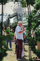 A lively festival scene with people gathered in a field surrounded by trees, creating a vibrant and joyful ambiance
