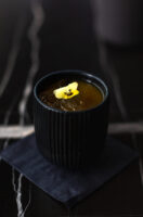 Black cup adorned with a yellow flower, perfect for a tasty beverage