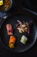 A plate of sushi, salad, and other delicious food.