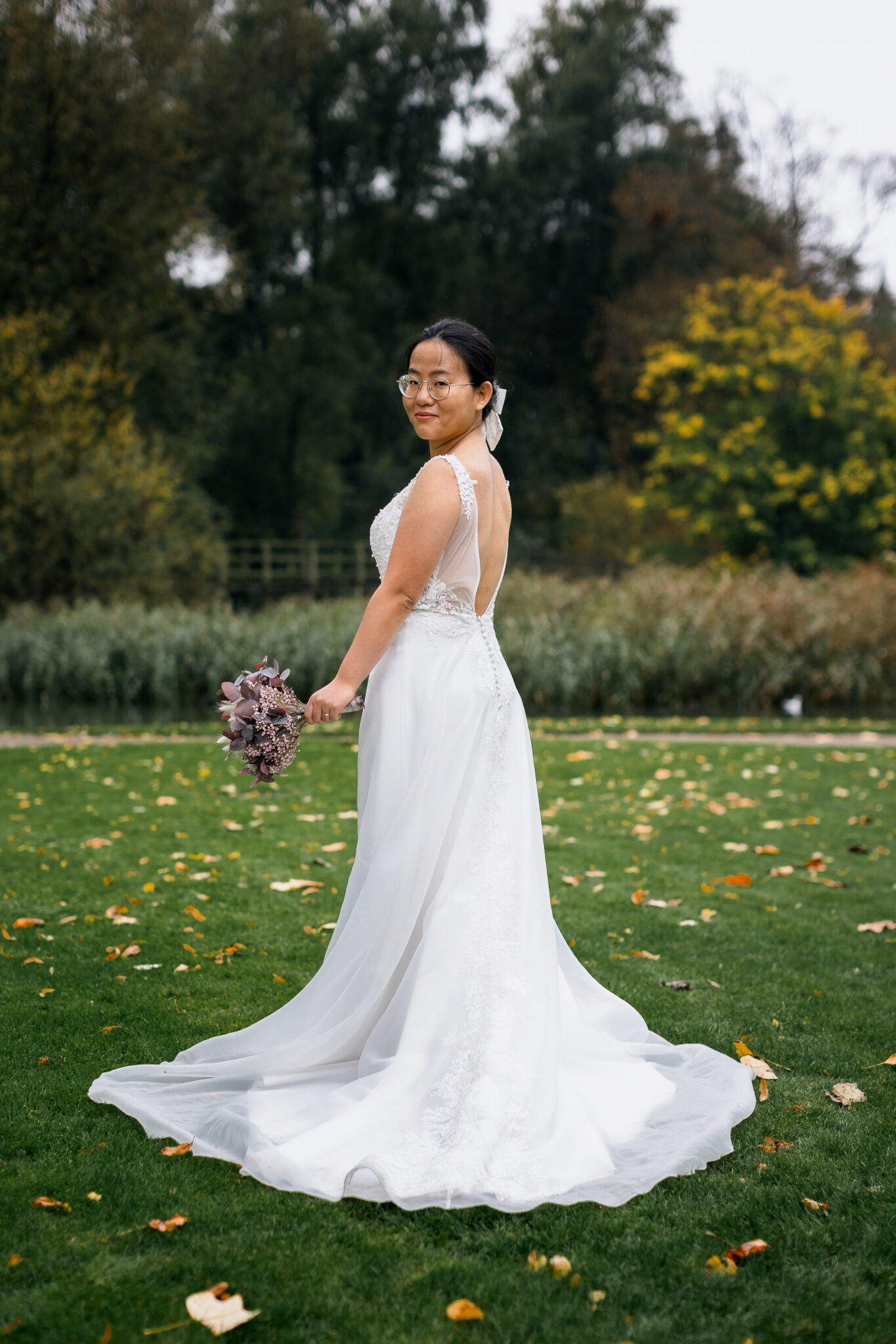An elegant bride wearing a white dress, standing on fresh green grass