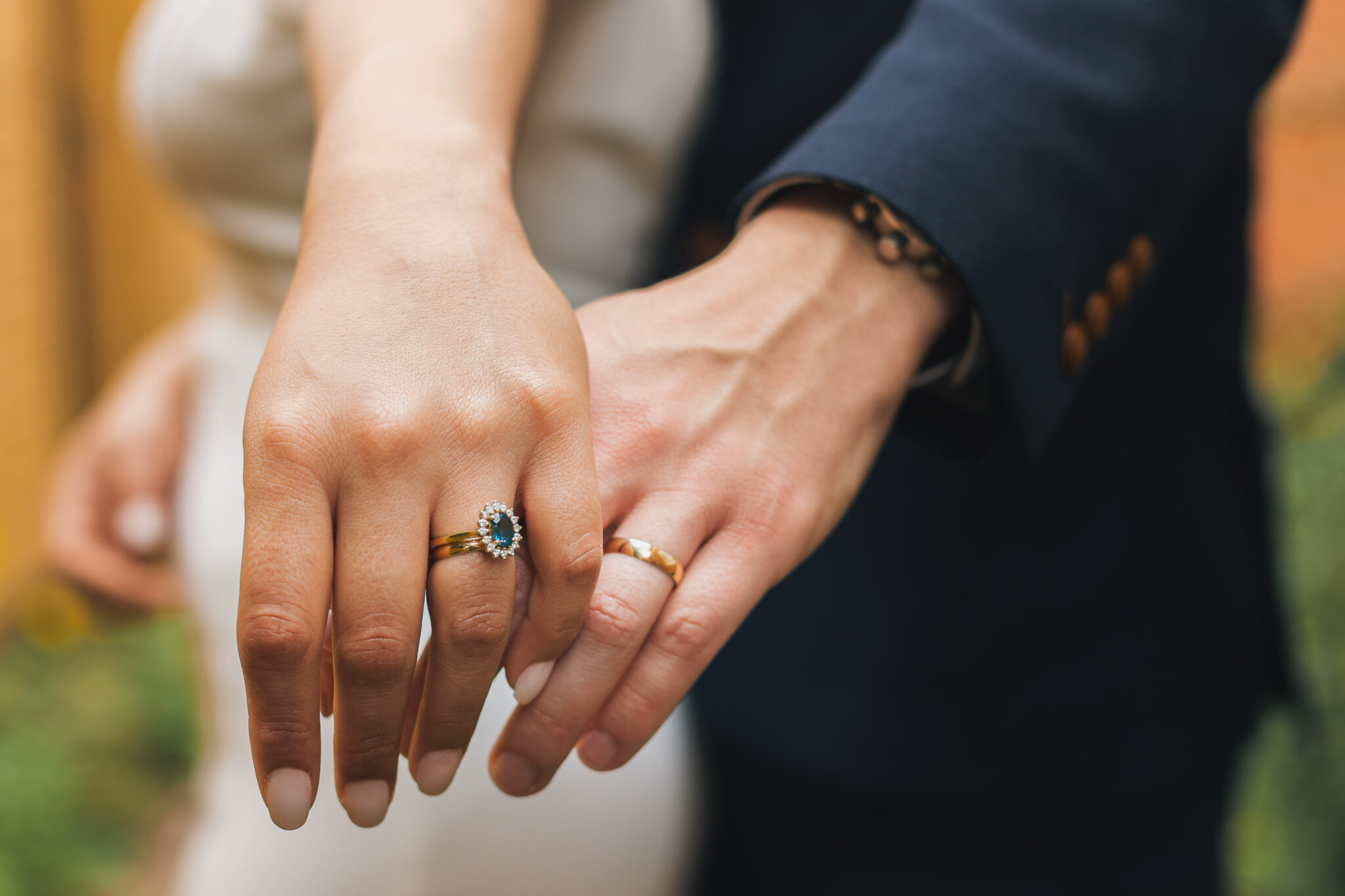A couple holding hands, displaying their wedding rings, symbolizing their commitment and love for each other.