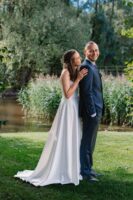 Bride and groom walking hand-in-hand along a garden path, smiling and enjoying their wedding day surrounded by lush greenery